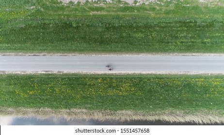 Aerial top down photo of couple cycling alongside each other over paved road showing grass fields on both sides of the path located in The Netherlands Holland during beautiful weekend day - Powered by Shutterstock