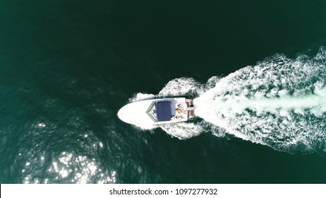 Aerial top down picture of motorboat with people sun tanning on stern side deck of boat also known as speedboat or powerboat is vessel which is powered by an engine beautiful summer day