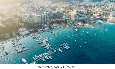 Aerial Top Down View Of Boat Dock And Yacht Port In Budva, Montenegro. White Private Motor Boats Are Moored To Pier On Adriatic Sea Coast. Yacht Club Boats Parking. Photo From Drone.