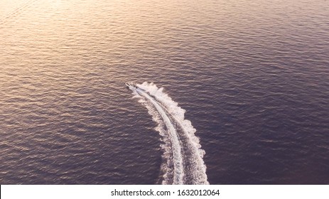 Aerial - Top Down View Of Catching Luxury Motor Boat Racing On The Water With Four People On It In Sunset