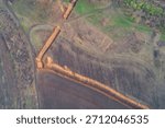 Aerial top down view of complex orange military trench system in field intersection. War zone defense fortification and high contrast earthworks texture.