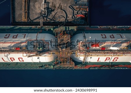 Aerial top down view of deck of LPG tanker ship with gas containers, moored at industrial port