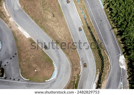Aerial top down view drone racing car driving on winding race track. Cloudy summer day. Kart racing open wheel motorsport. Racing go-karts competition