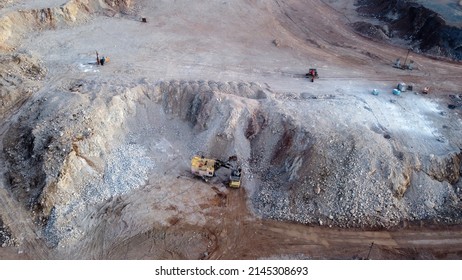 Aerial top down view of an excavator loading crushed stone into a dump truck in a crushed stone quarry. Aerial photography.