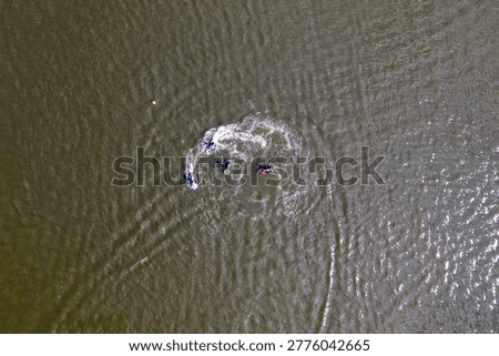 Aerial top down view of group of jet skiers making turns on water surface