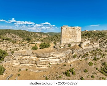 Aerial top down view of medieval Paracuellos de la Vega castle on the rocky hill in a valley in Spain with battlements