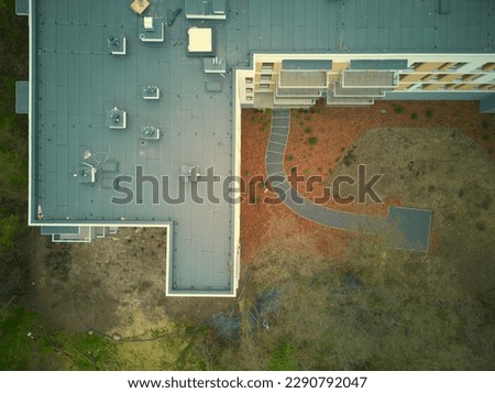 Aerial top down view of single apartment block during spring with walking paths. Drone photo.
