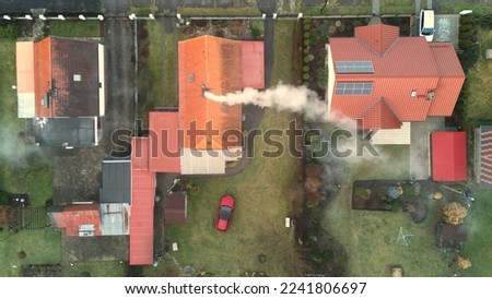 Aerial top down view of small town in Lower Silesia region of Poland. Clearly visible smoking chimneys of residential houses as a result of burning hard coal. House with solar panels on the roof. 