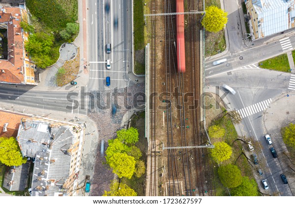 Aerial top down view of street\
intersection and train viaduct in motion blur in\
Lithuania