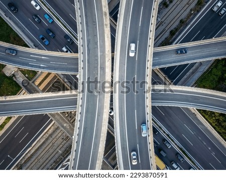 Aerial top down view of a symmetrical highway flyover interchange with many crossroads and curves as seen in Attiki Odos, Athens, Greece