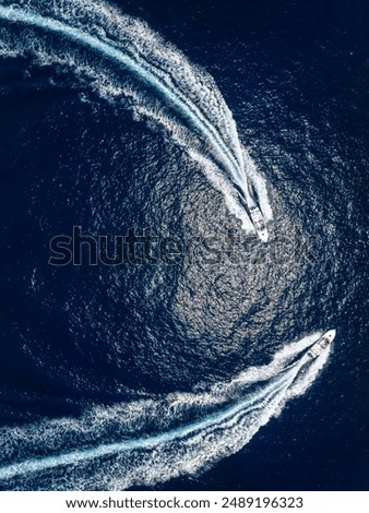 Aerial top down view of two motorboats cruising over the ocean with high speed and leaving a trail of bubbles