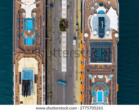 Aerial top down view of two luxury cruise ships docked at the port of Corfu, Greece. Highlighting swimming pools, sun loungers, and passengers on the top deck during a Mediterranean summer vacation