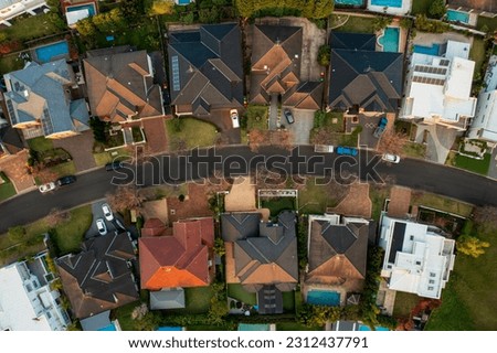 Aerial top down view of upmarket houses on a curved street in the fading winter sun in outer suburban Sydney, Australia.