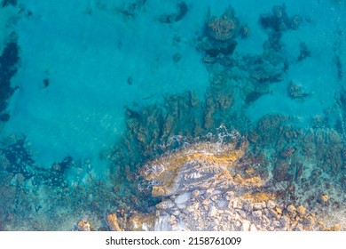 Aerial top down view of waves crashing against rocks in turquoise sea water - Powered by Shutterstock