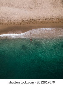 Aerial Top Down View Of Young Woman Laying In Crystal Clear Water During Summer Day.