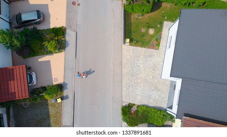 AERIAL TOP DOWN: Young Runners Living In The Suburban Neighborhood Jog Around The Block On A Sunny Summer Day. Healthy Man And Woman Jogging Down The Empty Street Leading Past Middle Class Row Houses.