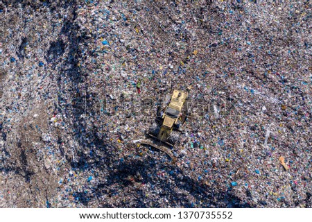 Aerial top drone view of large garbage pile, trash dump, landfill, waste from household dumping site, excavator machine is working on a mountain of garbage. Consumerism and contamination concept