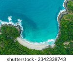 aerial top view amazing freedom beach small white sand beach with perfect nature. white wave hit the rock around island. green forest peaceful. green sea, and clear sand landscape. Paradise beach.