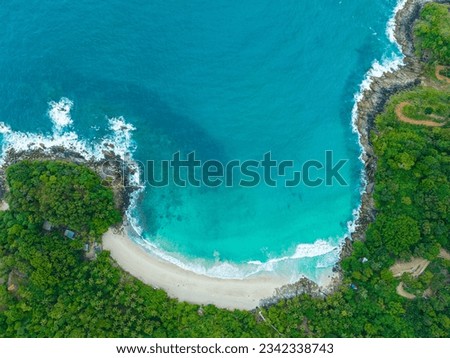 
aerial top view amazing freedom beach small white sand beach with perfect nature. 
white wave hit the rock around island. 
green forest peaceful. green sea, and clear sand landscape. Paradise beach.
