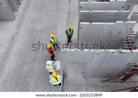 Aerial top view of architect and engineer discussing building plan at construction building site in warehouse factory. Precast concrete manufacturing products on prefabricated house factory