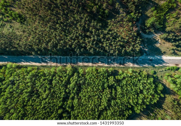 Aerial top view of asphalt road between green\
summer forest, drone shot,\
toned
