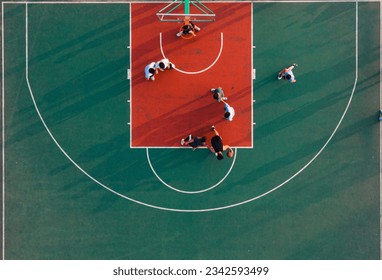 An aerial top view of a basketball court and young people playing the game - Powered by Shutterstock