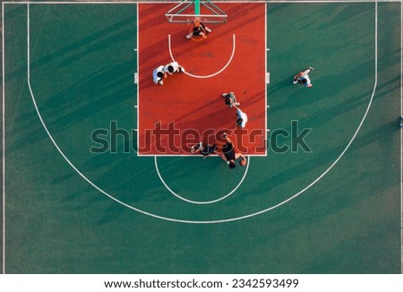 An aerial top view of a basketball court and young people playing the game