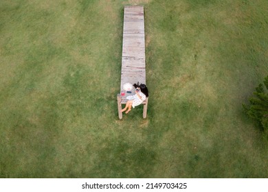 Aerial Top View Beautiful Asian Women And Cat Relaxing And Drinking Hot Coffee On The Wooden Bridge In The Garden Green Grass Background,