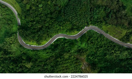 aerial top view beautyfull curve road on green forest in the rain season background, rural routes connecting cities in the north of thailand 