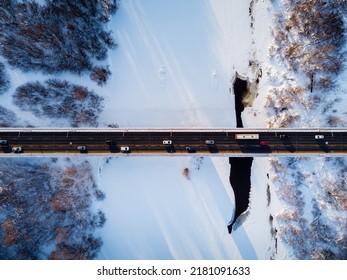 Aerial Top View Of Bridge Road Above Frozen River In Snow Winter Finland Lapland. Winter Season Aerial Top Down View Of A Bridge With A Straight Line Road Over River