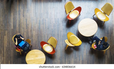 Aerial Top View Of Business People Sit On Chair With Table Desk With Laptop And Book In Public Space On The Interior Wood Furniture And Pattern Wood Floor.