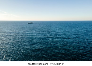 Aerial top view by drone of the sea with warship on horizon.