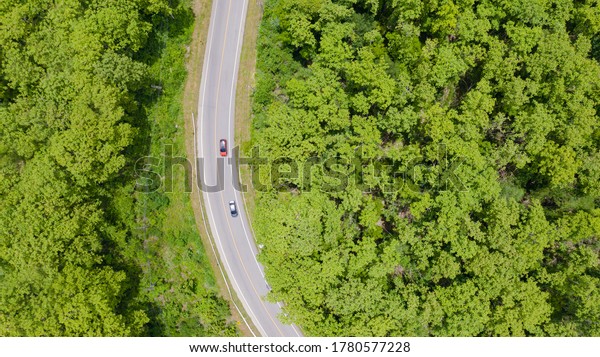 Aerial top view car driving through the forest on\
country road, view from\
drone