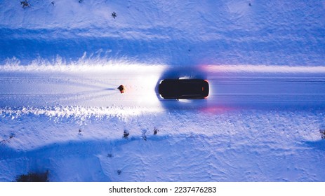 Aerial top view of car on rural area road while headlights are on in winter darkness, bird's eye view of suv vehicle in snowy north lands. Person standing front automobile which lighting the way - Shutterstock ID 2237476283