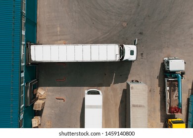 Aerial top view of cargo truck in industrial warehouse or logistic center waiting for loading goods.
