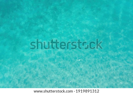 Aerial top view of clear blue turquoise seawater in summer season. Water in ocean. Surface pattern texture background.