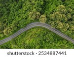 Aerial top view of countryside winding road passing through the green forest and mountain in Thailand. Ecology of system healthy environment road trip.