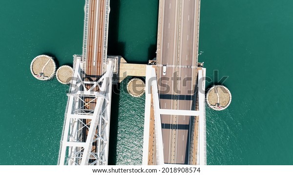 Aerial top view of the Crimean Bridge on\
turquoise water background. Shot. Passenger cars driving beautiful\
white bridge above Kerch\
strait.