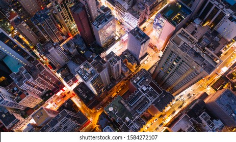 Aerial top view of downtown district  buildings in night city light. Bird's eye view from drone of cityscape metropolis infrastructure, crossing streets with parked cars. Development infrastructure