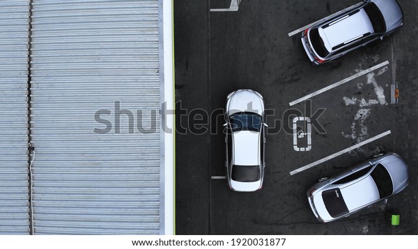 Aerial top view from drone\
places for disabled people on parking lot of the business center,\
shopping mall (supermarket) with cars and empty parking spots at\
day.