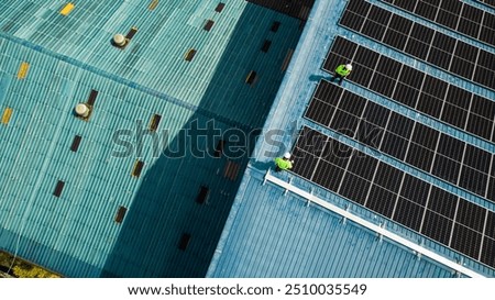 Aerial top view of engineer worker installing solar photovoltaic panels system on roof of the factory, Electric power industry renewable energy.