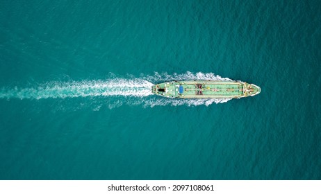 Aerial top view green Oil ship tanker full speed with beautiful wave and splash water in line of transportation from refinery on the sea.