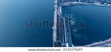 Aerial top view hydroelectric dam, water discharge through locks, blue color banner industrial concept.