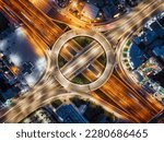 Aerial top view of a illuminated multilevel junction ring road as seen in Attiki Odos toll road motorway interchange with car traffic in Athens, Greece, during night time