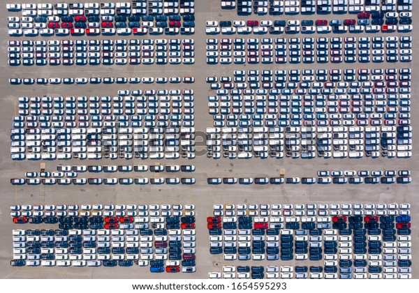 Aerial top view of  large number of new cars lined up\
outside an automobile factory ready to ship over sea. Cars export\
terminal in export and import business and logistics. Shipping\
cargo to harbor. 