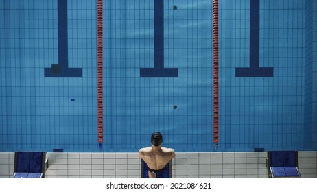 Aerial Top View Male Swimmer Swimmer Stanging on a Starting Block, Ready to Jump into Swimming Pool. Professional Athlete Winning World Championship. Top Down Shot. - Powered by Shutterstock