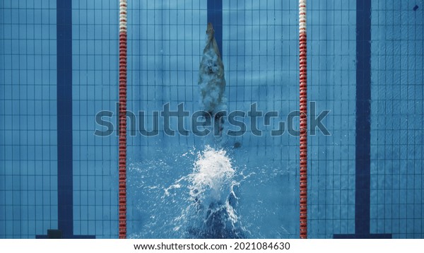 Aerial Top View Male Swimmer Jumping, Diving\
into Swimming Pool, Creating a Big Splash. Professional Athlete\
Winning World Championship. Top Down\
View.