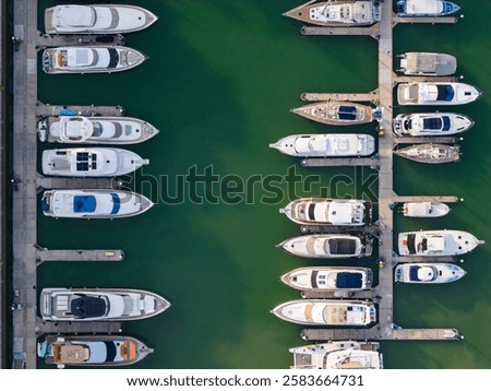 Aerial top view of a marina with luxury yachts and boats docked in neatly arranged rows.
