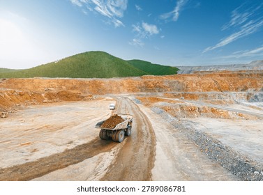 Aerial top view Mining dump truck transporting golden ore on curved haul road in open pit.