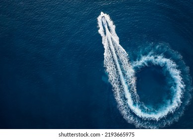 Aerial top view of a motor powerboat forming a circle of waves and bubbles with its engines over the blue sea - Shutterstock ID 2193665975